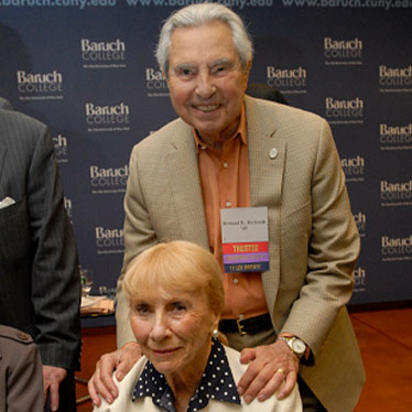 Couple taking photo together in front of Baruch wall. Read about Gifts of Life Insurance