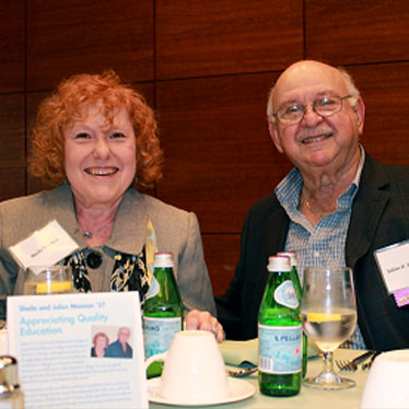Couple sitting at a dinner table and smiling. Read about Gifts from Retirement Plans